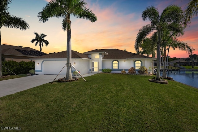 ranch-style home featuring a water view, a yard, and a garage