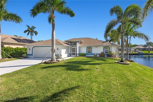 view of front of house featuring a garage, a front lawn, and a water view