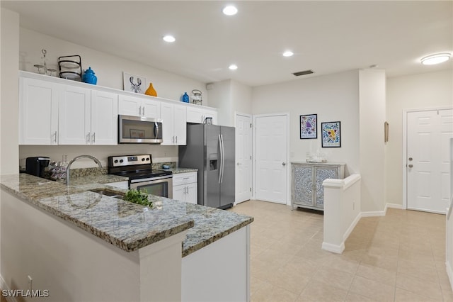 kitchen with appliances with stainless steel finishes, light stone countertops, white cabinets, light tile patterned flooring, and kitchen peninsula