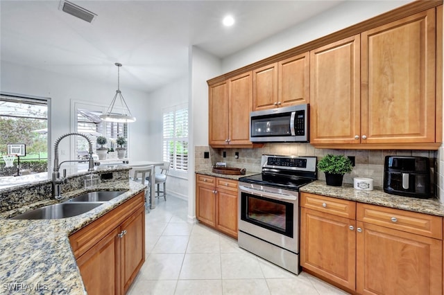 kitchen featuring sink, light stone counters, light tile patterned floors, and appliances with stainless steel finishes