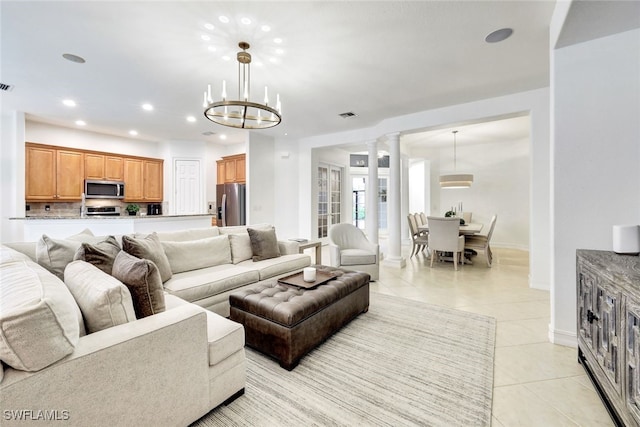 tiled living room featuring decorative columns and a chandelier