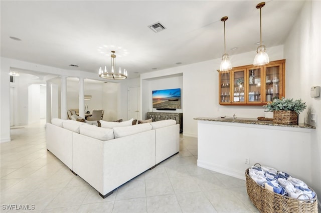 tiled living room with decorative columns and a chandelier