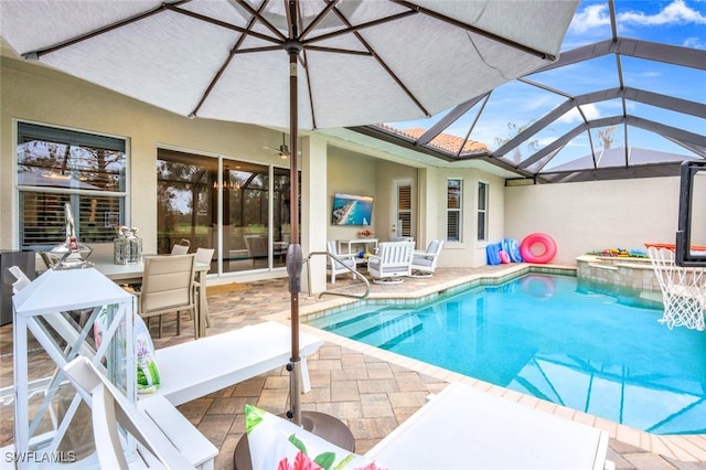 view of pool with glass enclosure, ceiling fan, and a patio