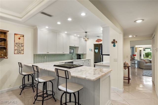 kitchen with light stone countertops, white cabinets, kitchen peninsula, and black appliances