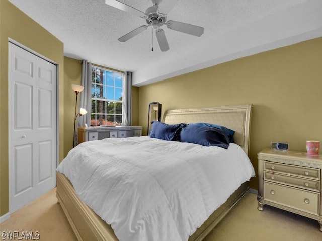 carpeted bedroom with ceiling fan, a closet, and a textured ceiling