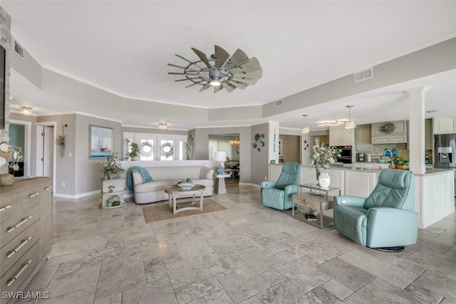 living room with a textured ceiling, ceiling fan, and crown molding