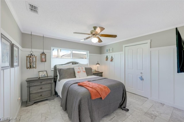 bedroom featuring a textured ceiling, ceiling fan, ornamental molding, and a closet