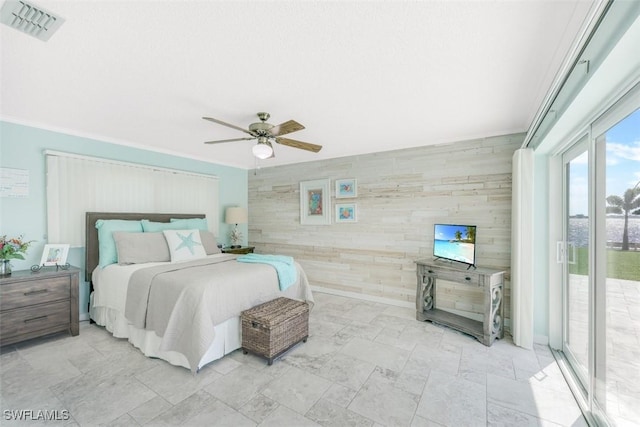 bedroom with ceiling fan, access to exterior, and wood walls