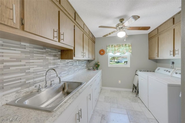 laundry area featuring washing machine and clothes dryer, ceiling fan, a textured ceiling, cabinets, and sink