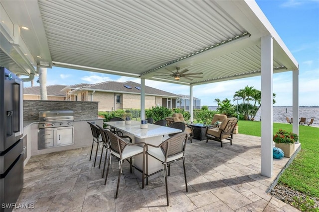 view of patio / terrace featuring ceiling fan, an outdoor kitchen, a water view, and area for grilling