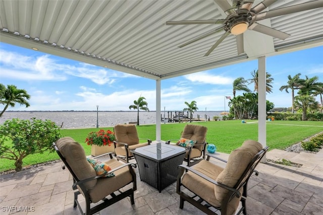 view of patio featuring ceiling fan, a water view, and an outdoor living space with a fire pit