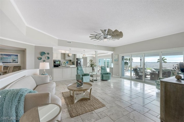 living room featuring ceiling fan, a textured ceiling, and a healthy amount of sunlight