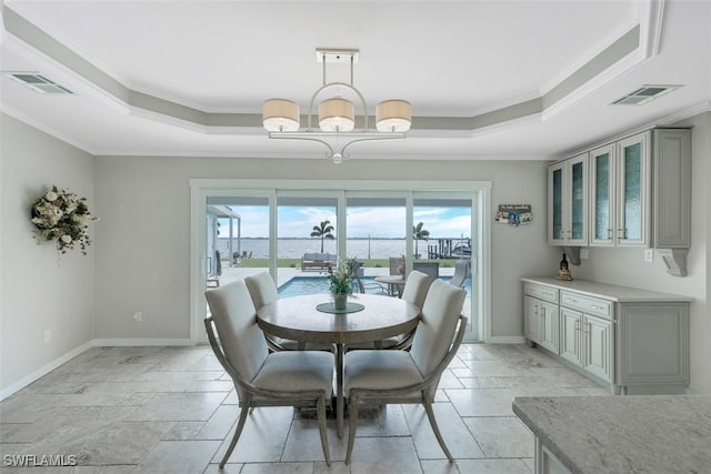 dining room featuring crown molding, a raised ceiling, and a notable chandelier