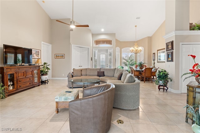 tiled living room with ceiling fan with notable chandelier and a high ceiling