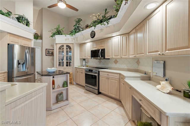 kitchen with ceiling fan, appliances with stainless steel finishes, tasteful backsplash, light tile patterned flooring, and a center island