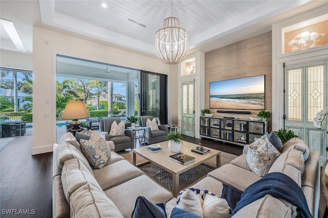 living room featuring a raised ceiling, a chandelier, and dark hardwood / wood-style flooring