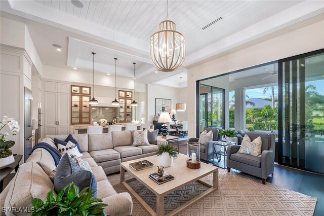 living room featuring light hardwood / wood-style flooring, a notable chandelier, wood ceiling, and a tray ceiling