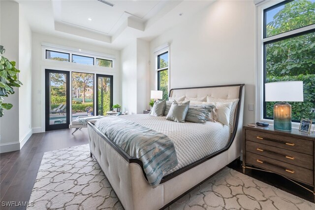 bedroom featuring access to outside, a raised ceiling, wood-type flooring, and a high ceiling