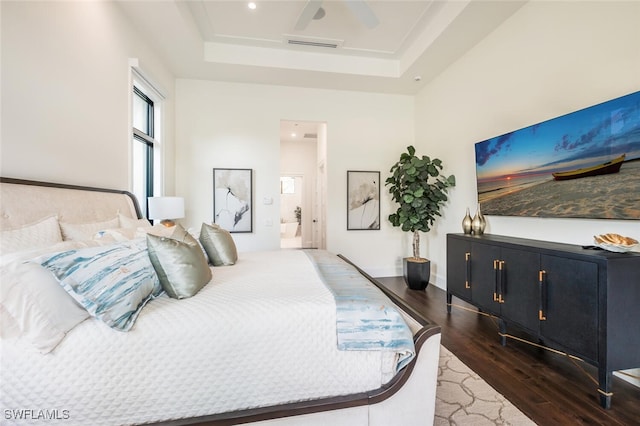 bedroom featuring ceiling fan, a towering ceiling, ensuite bathroom, a tray ceiling, and dark hardwood / wood-style flooring