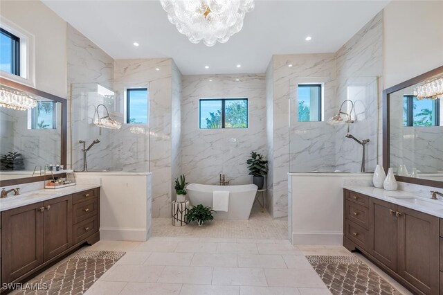 bathroom featuring a tub to relax in, a wealth of natural light, tile walls, and a notable chandelier