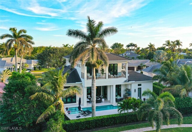 rear view of property featuring a fenced in pool, a patio, and a balcony