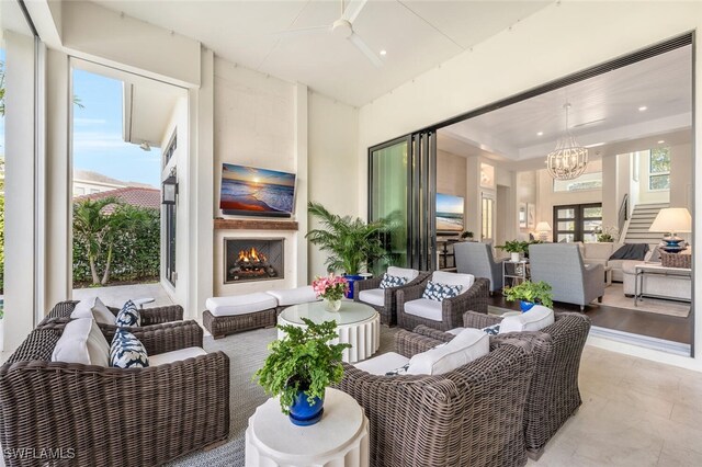 living room with a chandelier, a wealth of natural light, exterior fireplace, and a tray ceiling