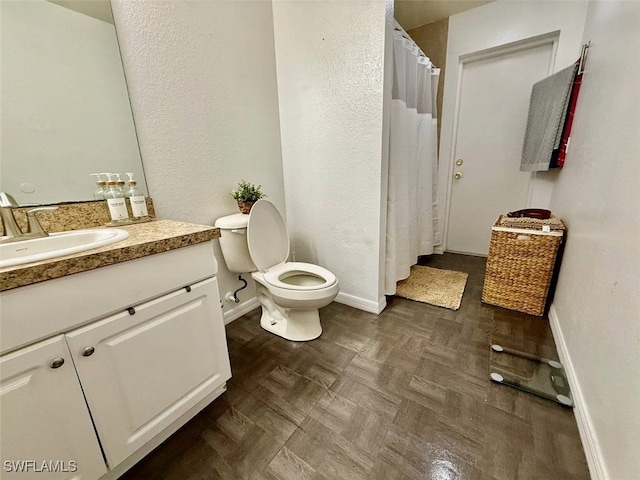 bathroom with toilet, vanity, and parquet floors