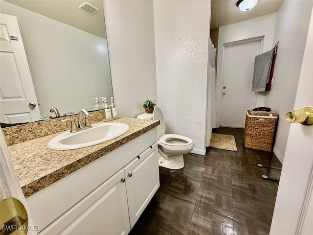 bathroom with parquet flooring, toilet, and vanity