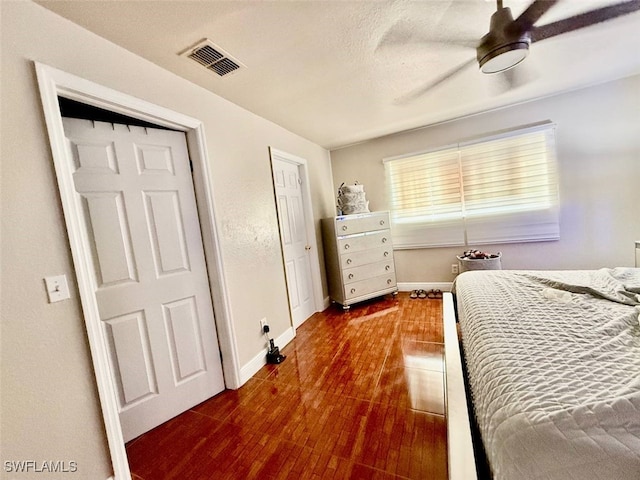 bedroom with ceiling fan, a textured ceiling, and dark hardwood / wood-style flooring