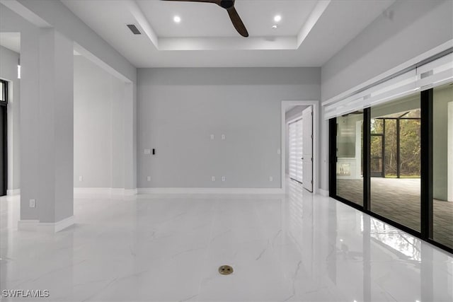 spare room featuring ceiling fan and a raised ceiling