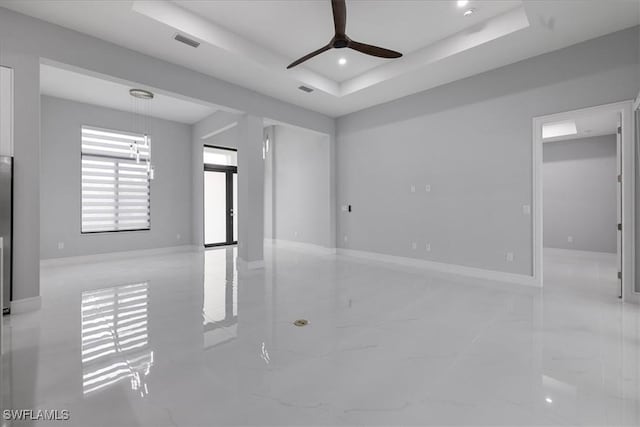 spare room featuring ceiling fan and a raised ceiling