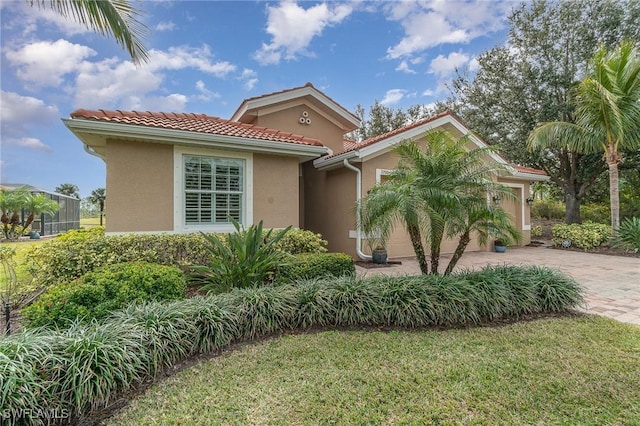 3200 Magnolia Landing Ln, North Fort Myers, FL 33917 - mediterranean / spanish home featuring stucco siding, driveway, an attached garage, a tile roof, and a front lawn