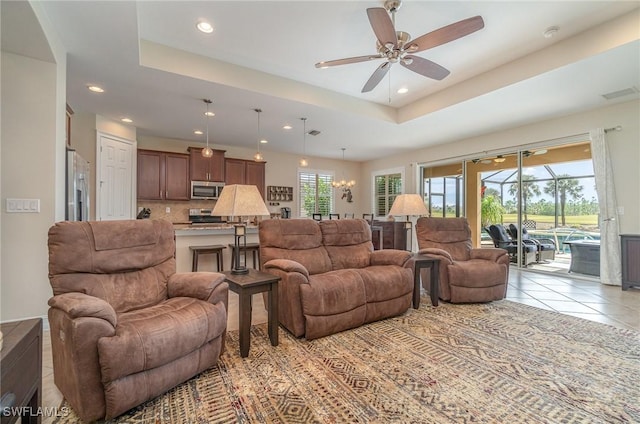 living room featuring a tray ceiling, ceiling fan, and light tile patterned flooring