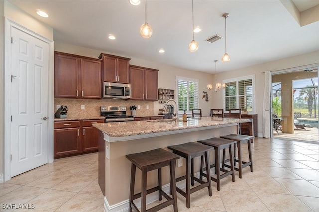 3200 Magnolia Landing Ln, North Fort Myers, FL 33917 - kitchen featuring appliances with stainless steel finishes, backsplash, light tile patterned floors, light stone counters, and recessed lighting