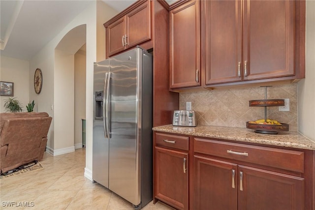3200 Magnolia Landing Ln, North Fort Myers, FL 33917 - kitchen with stainless steel fridge, arched walkways, decorative backsplash, light stone countertops, and light tile patterned floors