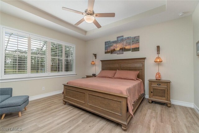 3200 Magnolia Landing Ln, North Fort Myers, FL 33917 - bedroom with light wood-style floors, a tray ceiling, and a ceiling fan