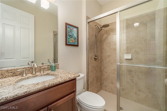 bathroom featuring toilet, vanity, and a shower with shower door