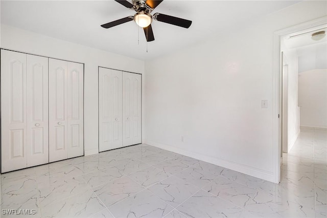 unfurnished bedroom with multiple closets and ceiling fan