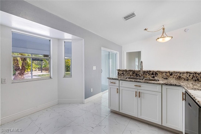 kitchen with decorative light fixtures, sink, white cabinets, dark stone counters, and stainless steel dishwasher