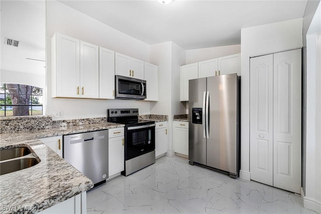 kitchen with light stone countertops, appliances with stainless steel finishes, sink, and white cabinets