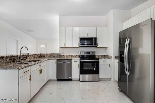 kitchen with white cabinets, stainless steel appliances, sink, and dark stone countertops