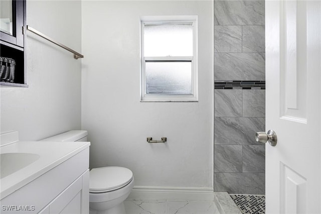 bathroom featuring vanity, tiled shower, and toilet