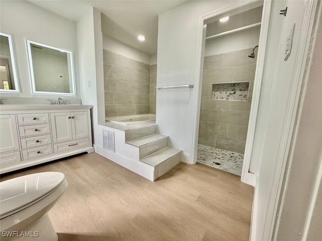 bathroom with hardwood / wood-style floors, independent shower and bath, and vanity