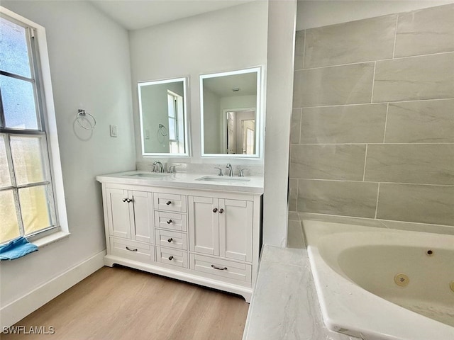 bathroom with a relaxing tiled tub, hardwood / wood-style floors, and vanity