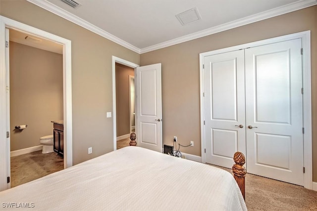 carpeted bedroom featuring ensuite bath, a closet, and crown molding