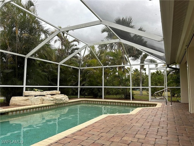 view of swimming pool featuring glass enclosure and a patio area