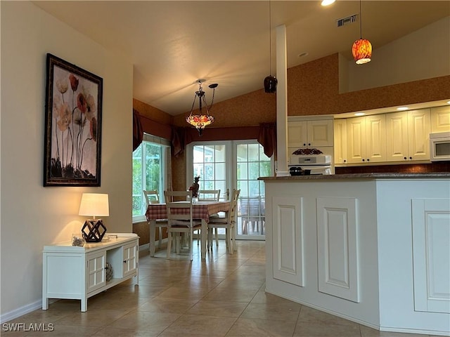 kitchen with decorative light fixtures, white cabinets, white oven, and vaulted ceiling