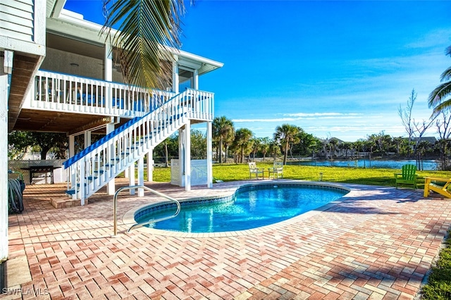 view of swimming pool with a water view, a patio area, and a yard