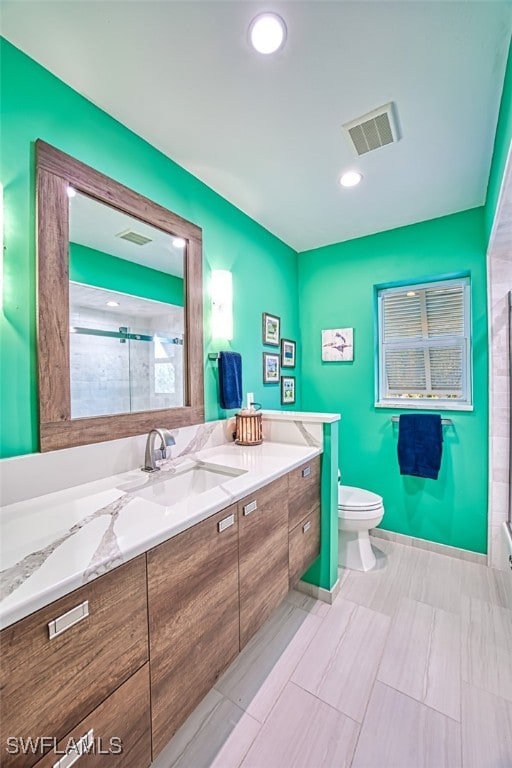 bathroom featuring a shower with shower door, toilet, and vanity