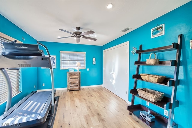 exercise room with light wood-type flooring and ceiling fan